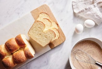 Sliced brioche next to eggs and mixing bowl